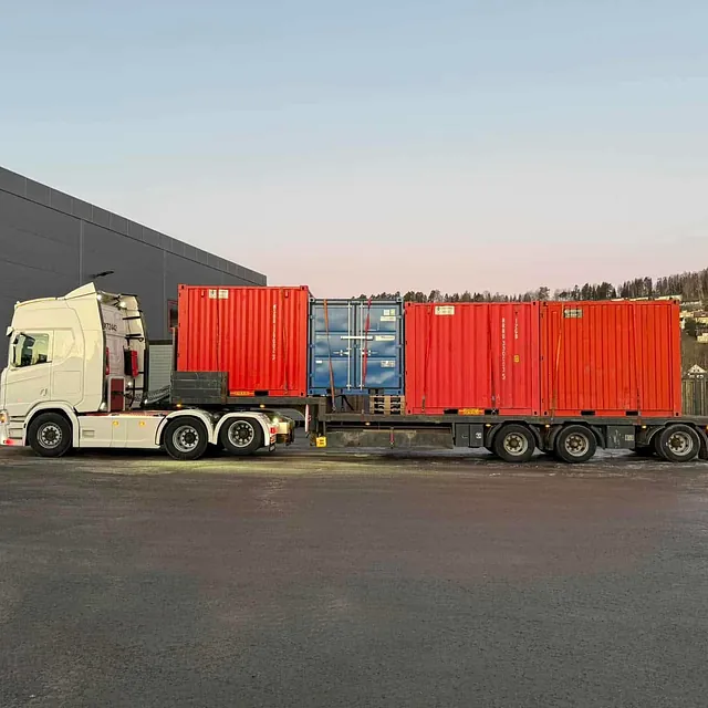 Hvit lastebil med røde containere på henger.